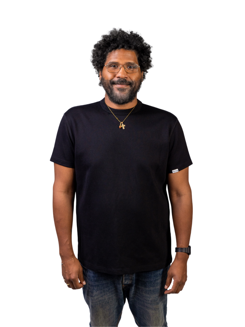 Smiling man wearing a black TG1 T-shirt with jeans and a necklace